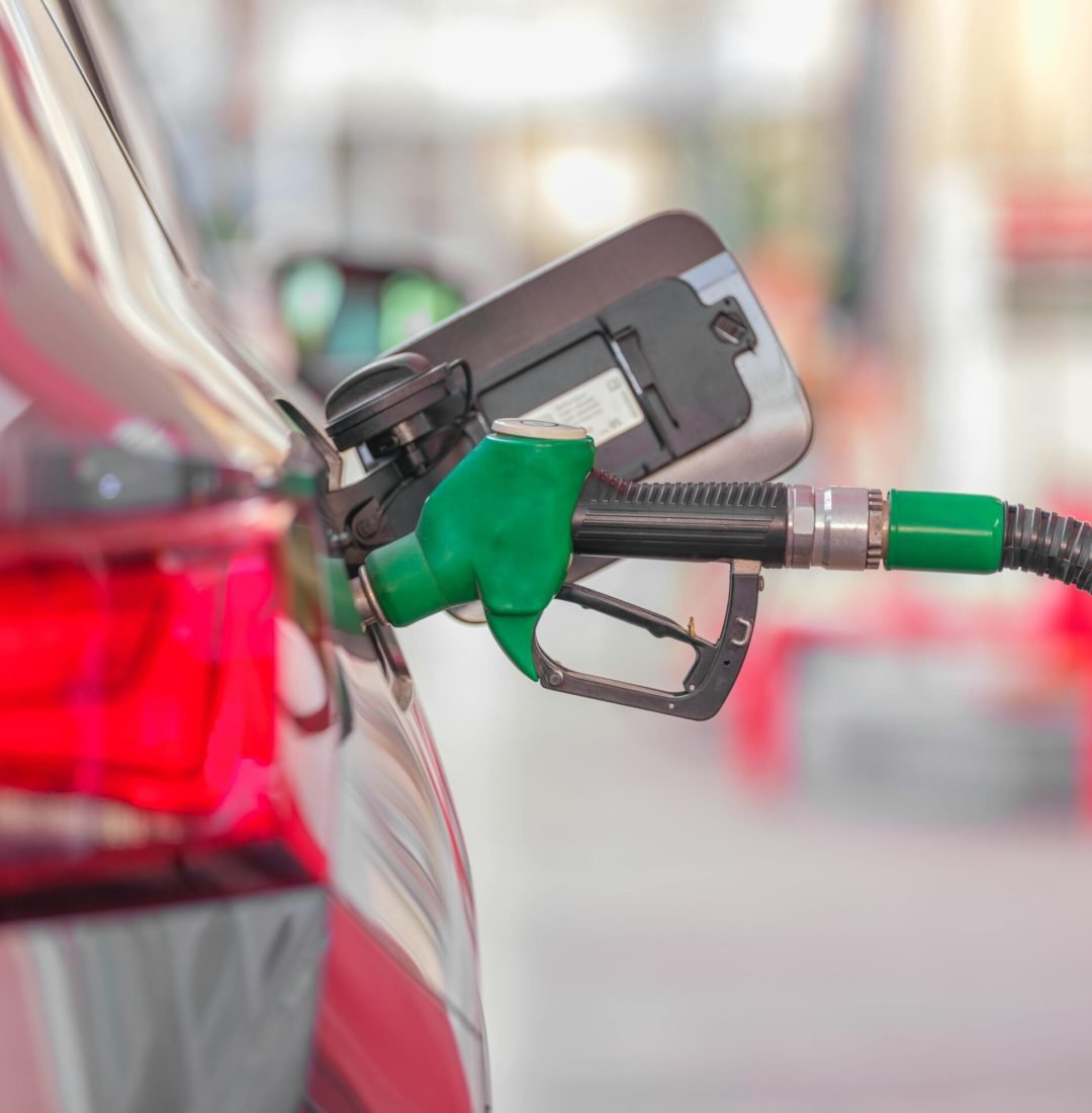 A close-up view of a fuel pump nozzle inserted into a car's tank at a gas station.