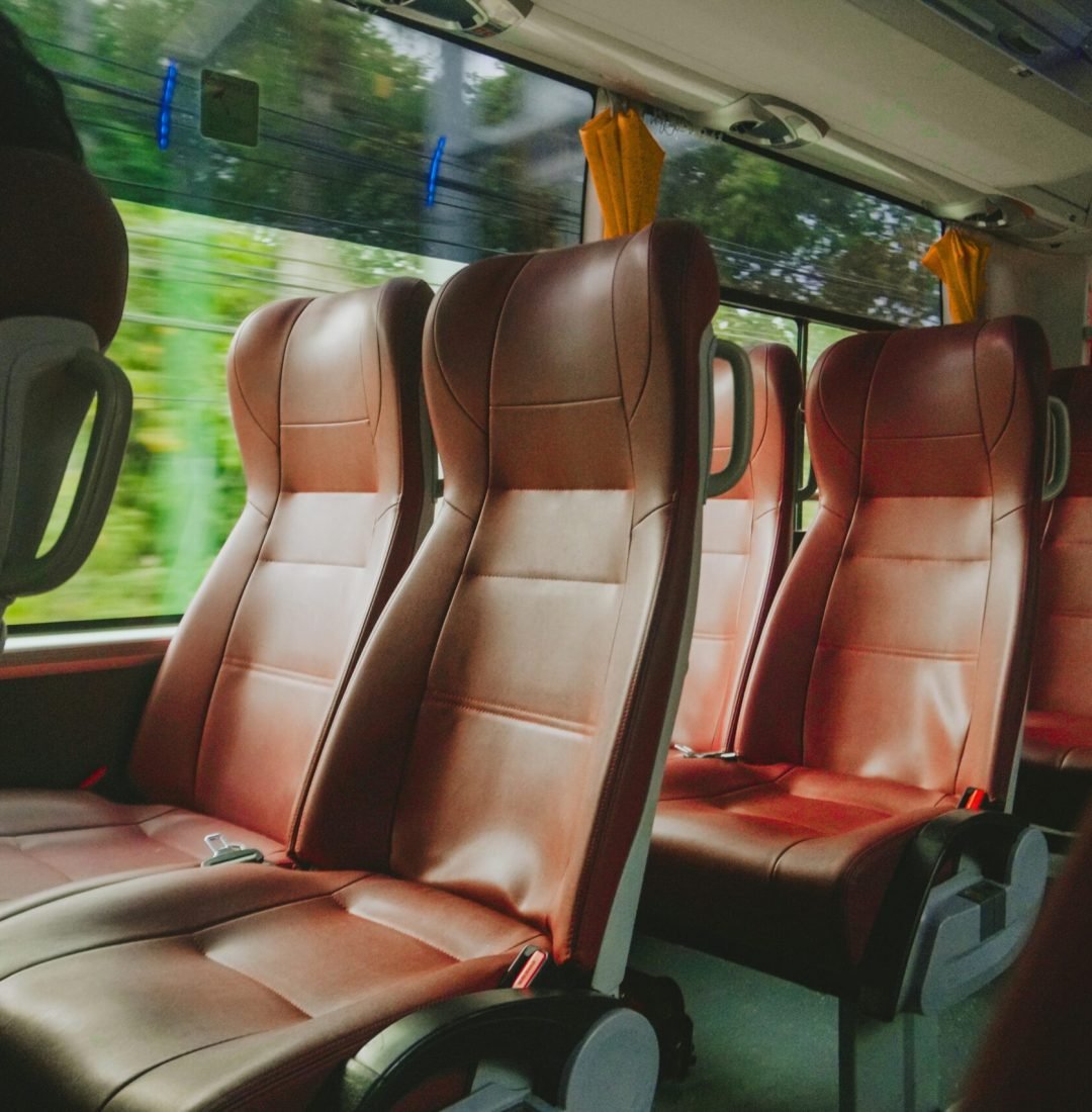Interior view of a luxurious bus with empty red leather seats, offering comfort and style.